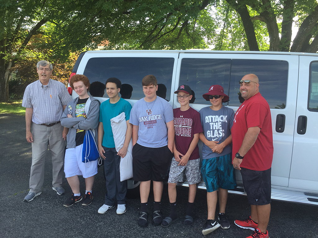 5 teenage boys and two adult males in front of a van