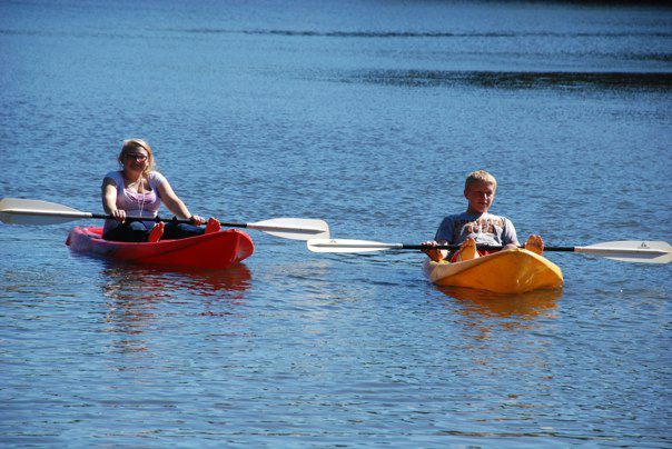 Two students glide in canoes across the lake