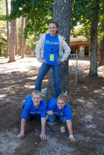 One student stands on the backs of two kneeling students