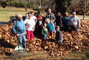 Church members standing in leaves to be raked