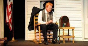 man in a rocking chair on the porch, listening to radio