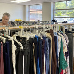 Sharon looks through clothing hanging on racks