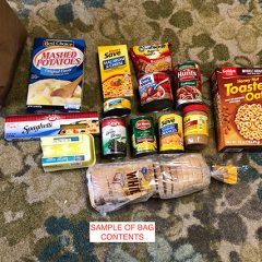 Contents of grocery bag displayed: mashed potatoes, macaroni and cheese, canned goods, cereal, eggs, peanut butter, a loaf of bread