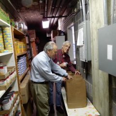 Two men organize pantry shelves