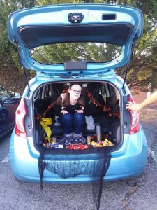 Madison sits in the back of her hatchback, wearing monster feet shoes.