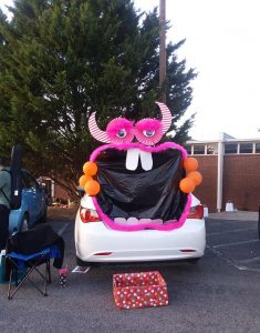 Car decorated with big mouth and teeth, orange balloons, and pink poster board eyes