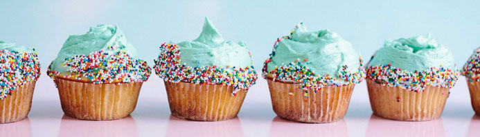 a row of blue cupcakes decorated with colorful sprinkles