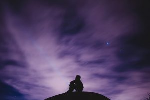 Person sitting alone against a dark night sky