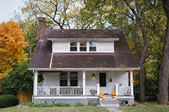 white house with gray roof; orange pumpkins on the porch