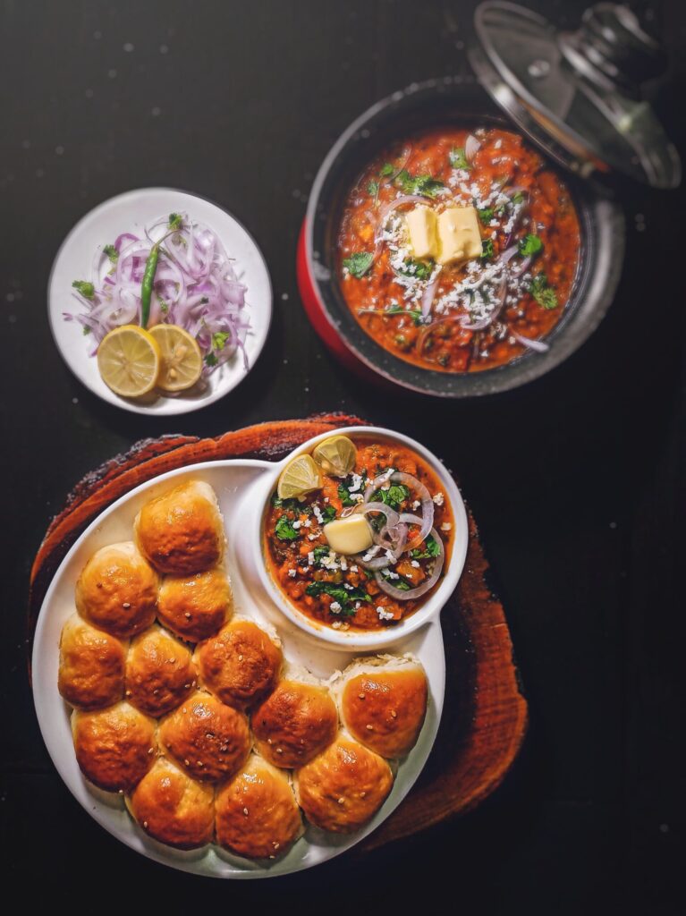 White buns on a platter with a dish of a vibrant vegetable stew