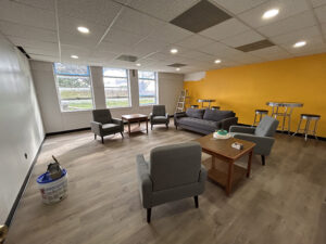 Large classroom with gray furniture and a yellow accent wall
