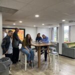 People smiling while standing and sitting at a tall table