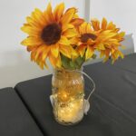 Yellow flowers in a glass jar with sparkling lights