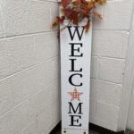 Narrow welcome sign with fall leaves at the top